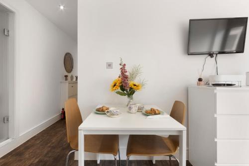 a white dining room table with chairs and a vase of flowers at Green Lanes Studios By Morethanstays in London