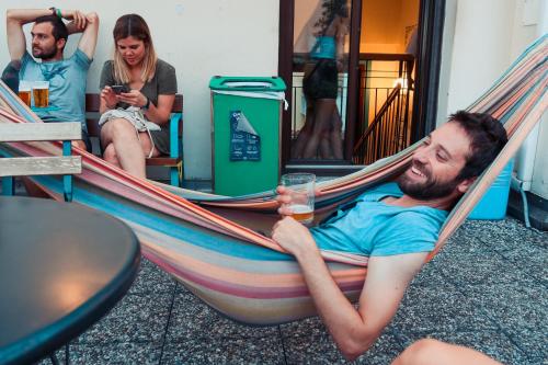 a man laying in a hammock with a glass of beer at Ostello Bello Milano Centrale in Milan
