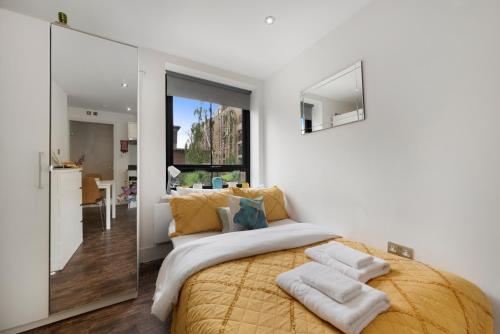 a bedroom with a large yellow bed and a mirror at Green Lanes Studios By Morethanstays in London