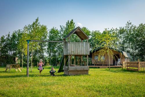 a child playing on a swing set in a yard at Glamping Hoeve Klein Haneveld in Sint-Oedenrode