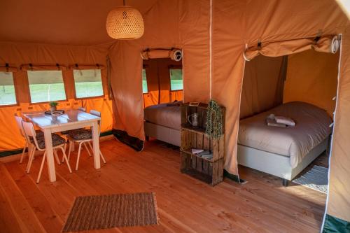 a room with a bed and a table in a tent at Glamping Hoeve Klein Haneveld in Sint-Oedenrode