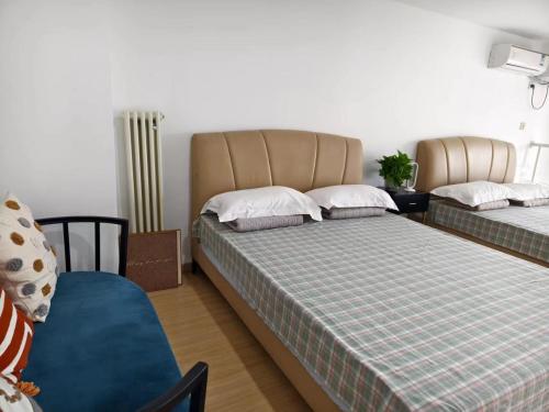 a bedroom with two beds and a chair and a radiator at Chaoyang Joy City Hardcover Apartment in Beijing