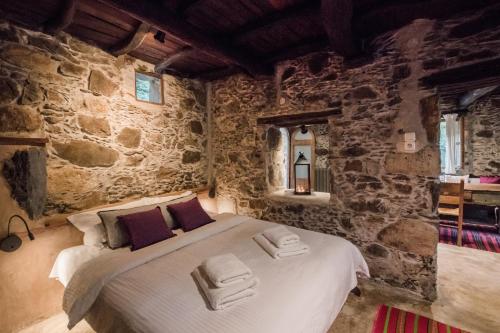 a bedroom with a bed in a stone wall at Μilia Mountain retreat in Vlátos