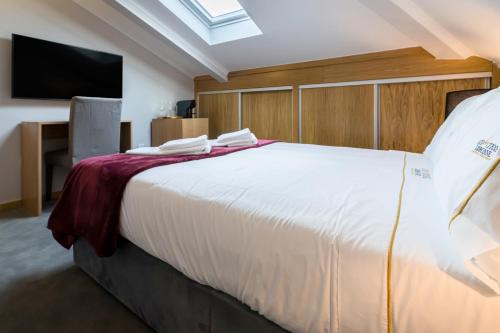 a bedroom with a large white bed and a flat screen tv at Comtesse Lisbonne Guest House by Homing in Lisbon