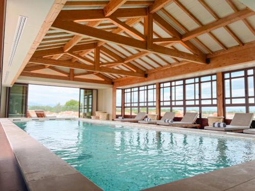 - une grande piscine avec des chaises dans un bâtiment dans l'établissement Relais et Châteaux Thalasso & Spa Ile de la Lagune, à Saint-Cyprien