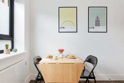 a table and two chairs in a room with pictures on the wall at Green Lanes Studios By Morethanstays in London