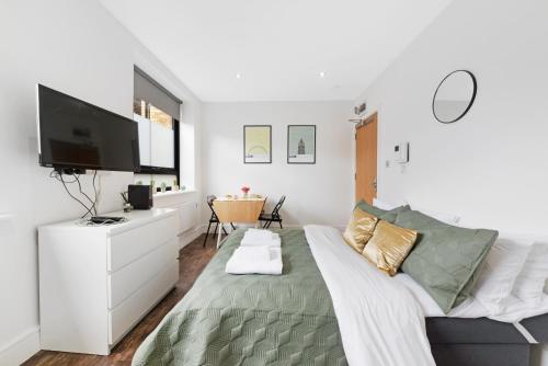 a white bedroom with a bed and a flat screen tv at Green Lanes Studios By Morethanstays in London