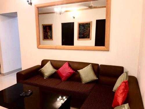 - un salon avec un canapé brun et un miroir dans l'établissement Golden Sun Ray's Villas, à Baga