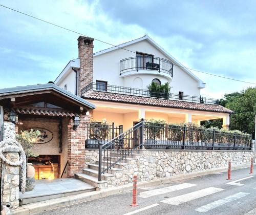 a large white house with a stone wall at Bracera Inn in Malinska