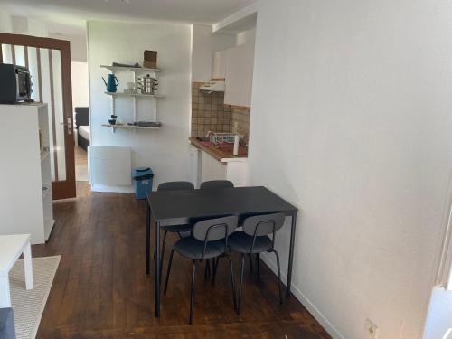- une table et des chaises noires dans une petite cuisine dans l'établissement Haut de jardin dans une maison, à Dijon