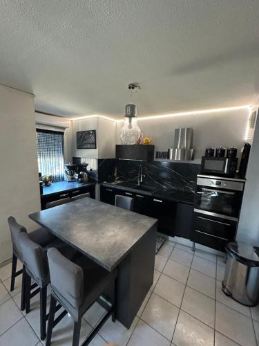 une cuisine avec un comptoir noir et une table dans l'établissement appartement climatisé, à Avignon