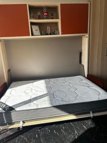 un lit vide dans une pièce avec une étagère dans l'établissement Studio climatisé belle vue mer, à Ajaccio