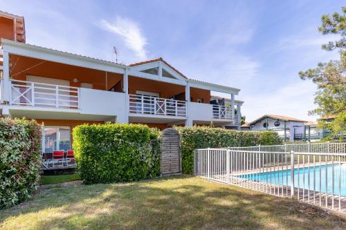 un immeuble d'appartements avec piscine et buissons dans l'établissement Appartement Fred, à Moliets-et-Maa