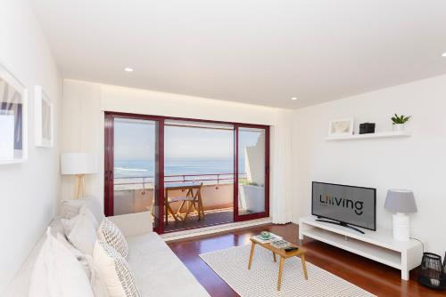 ein Wohnzimmer mit einem weißen Sofa und einem TV in der Unterkunft Liiiving in Matosinhos - Seaside Balcony Apartment in Porto