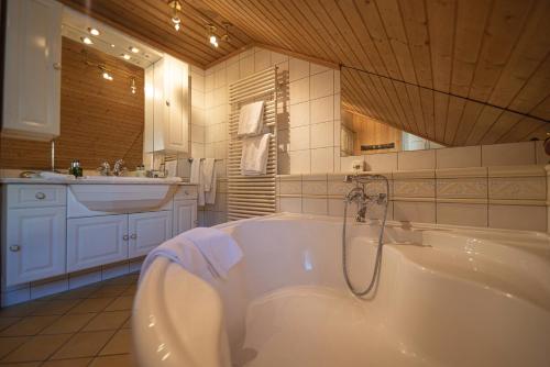 um banheiro branco com banheira e pia em Ferienwohnungen im Boutique-Hotel Alpenrose em Schönried