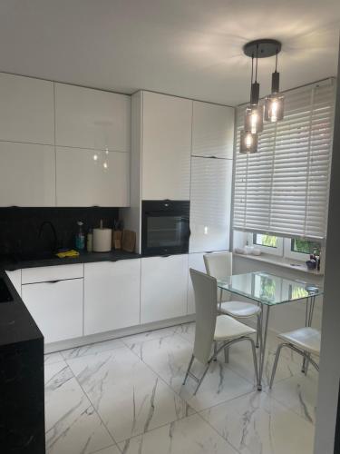 a kitchen with a glass table and white cabinets at Villa Klimontów in Klimontów