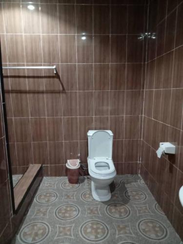a bathroom with a toilet and a tiled wall at Koohan Hotel in Bibiani
