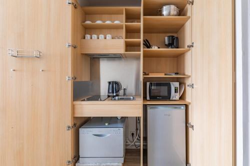 une cuisine avec des armoires en bois et un réfrigérateur dans l'établissement Appart'City Classic Reims Parc des Expositions, à Reims