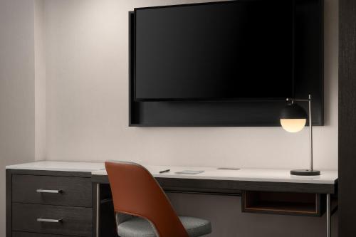 a desk with a chair and a television on a wall at Courtyard New Haven at Yale in New Haven