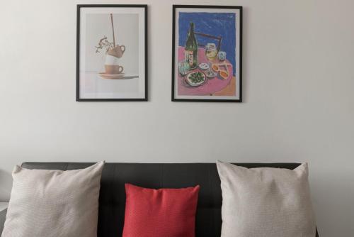 three framed pictures on a wall above a couch with pillows at Studio 6- Archway Station in London