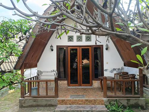 a small house with wooden doors and a tree at Noby Gili Cottages in Gili Meno