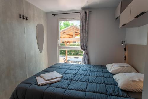 a bedroom with a blue bed and a window at CAMPING & SPA CAP SOLEIL in Vias