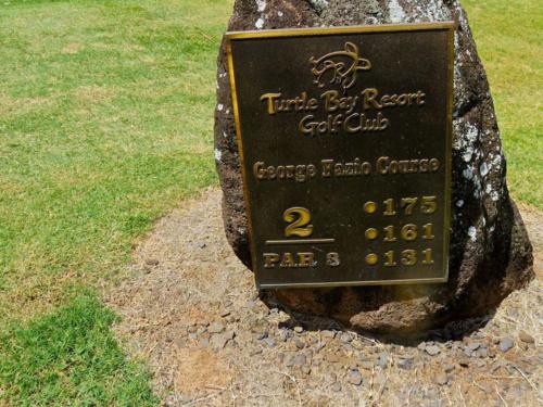 a sign on a rock in the grass at Ocean Pearl in Kahuku