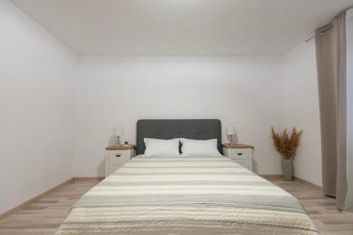 a white bedroom with a large bed with two night stands at Casa lui Matei Murighiol in Murighiol