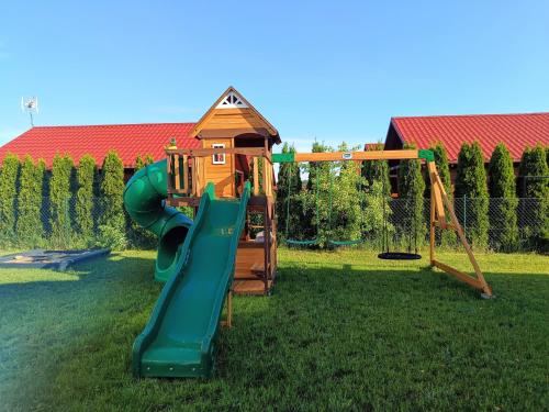 een speeltuin met een glijbaan en een speelhuis bij Bałtyk i Las in Rusinowo