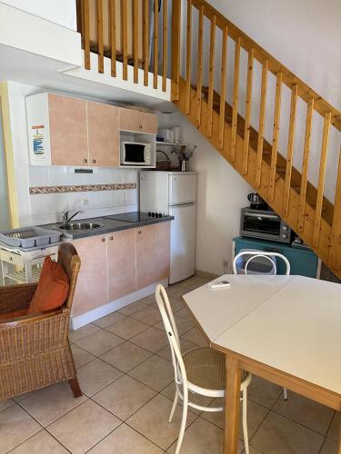 une cuisine et une salle à manger avec une table et un escalier dans l'établissement HOLIDAYLAND VILLA 439 T2 MEZZANINE 6 couchages climatisé NARBONNE PLAGE, à Narbonne-Plage