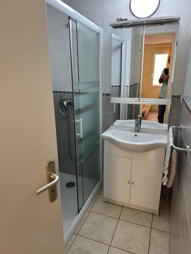 une femme prenant une photo d'une salle de bains avec lavabo et douche dans l'établissement HOLIDAYLAND VILLA 439 T2 MEZZANINE 6 couchages climatisé NARBONNE PLAGE, à Narbonne-Plage