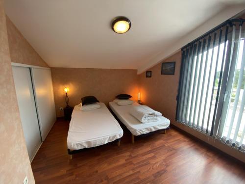 - 2 lits dans une chambre avec de grandes fenêtres dans l'établissement Appartement entre mer et pins - PARKING, à Les Sables-dʼOlonne