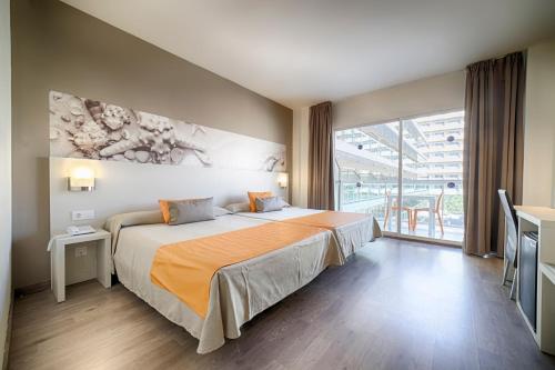 a hotel room with a bed and a large window at Ohtels Villa Dorada in Salou