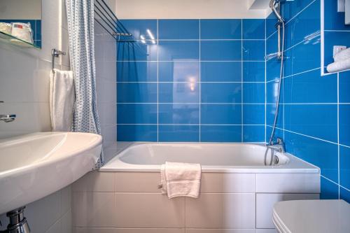baño de azulejos azules con bañera y aseo en Hotel Coté Sud en Saint-Péray