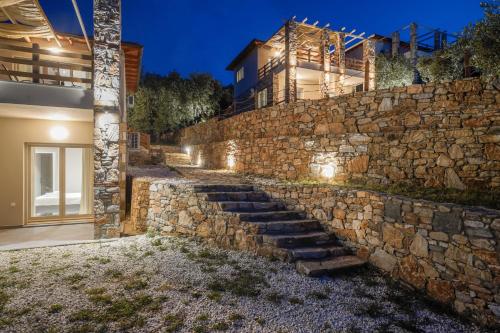a stone wall with stairs leading up to a house at Helicon Luxury Villas in Limenas