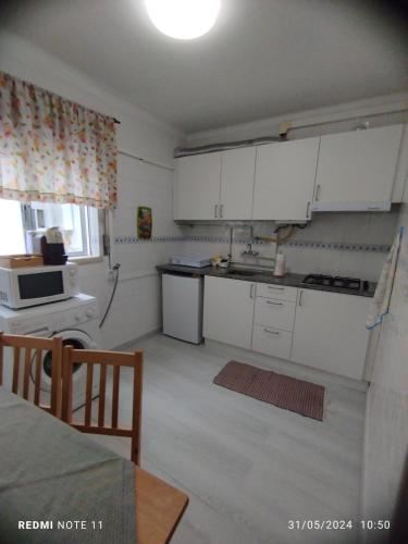 a small kitchen with white cabinets and a table at Apartamentos das Avós-Flor in Nazaré
