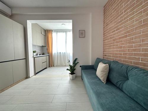 ein Wohnzimmer mit einem grünen Sofa und einer Ziegelwand in der Unterkunft TreA Accomodations - Suite port in Vlorë