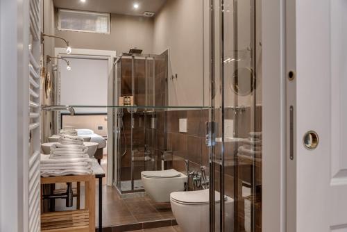 een badkamer met 3 toiletten en een glazen douche bij B&b L' Orangerie in Pietrasanta