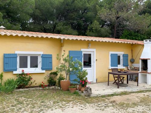 une maison jaune avec des volets bleus et une table dans l'établissement Maisonnette La Couronne plage, à Martigues