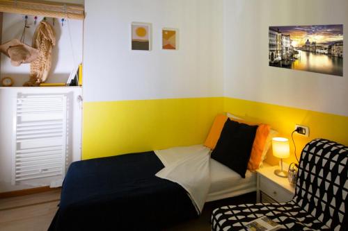 a small bedroom with a bed and a chair at La Perla del Sole - Sunset on the beach in Lido di Pomposa