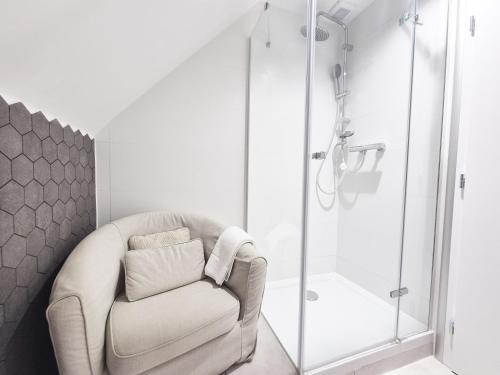 a white bathroom with a chair and a shower at Hotel Desatero in Mikulov