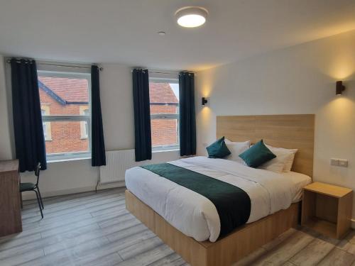 a bedroom with a large bed and two windows at Crown House in Oxford