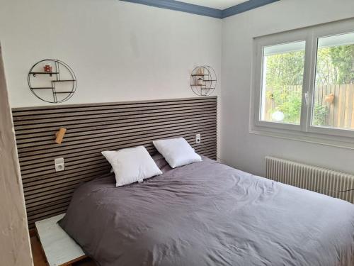 a bedroom with a large bed with two pillows at Duplex près des Thermes avec jardin in Évian-les-Bains