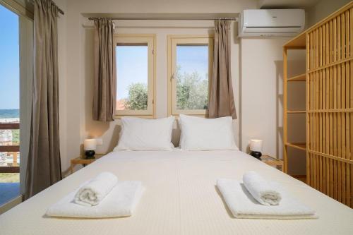 a bedroom with a large white bed with towels on it at Helicon Luxury Villas in Limenas