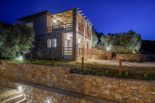 a house with a stone wall at night at Helicon Luxury Villas in Limenas