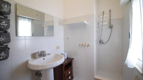 Un baño blanco con lavabo y ducha. en La Casa di Anita, en Orosei