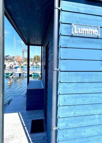 a blue building with a dock with a marina at Hausboot LUMME - Huus & Meer in Großenbrode