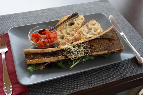 a plate with a sandwich and a bowl of salsa at Borhotel Sziluett Farkasmály in Gyöngyös