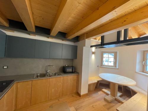 uma cozinha com armários de madeira, um lavatório e uma mesa em Chalet Le Grazie em Le Grazie