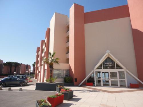 un bâtiment avec une voiture garée sur un parking dans l'établissement Appartement climatisé avec vue mer et piscine, à Sète